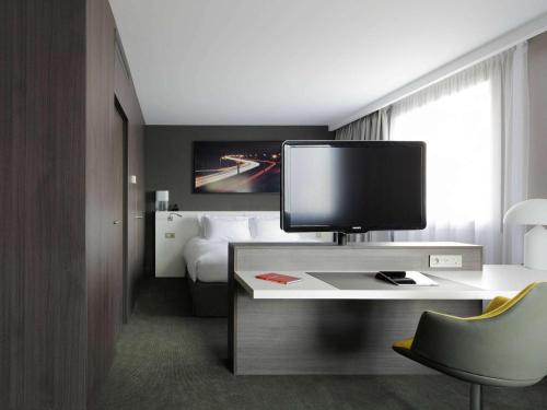a hotel room with a desk with a television on it at Pullman Paris La Défense in Courbevoie