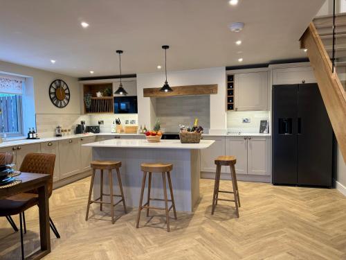a kitchen with a large island with bar stools at Beudy Pwll Pridd in Corwen