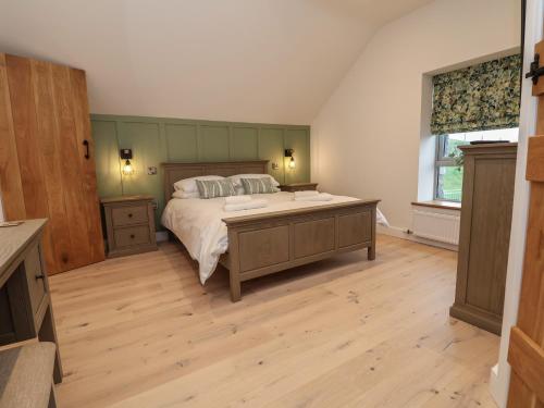 a bedroom with a large bed and a wooden floor at Beudy Pwll Pridd in Corwen