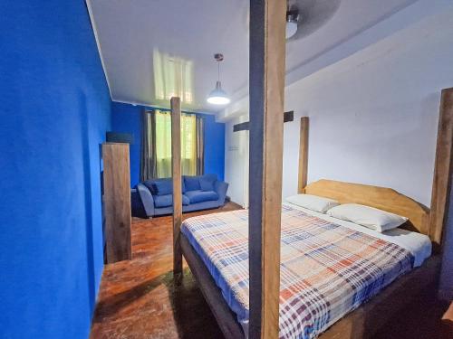 a bedroom with a bed and a blue wall at Tree House Beachfront Lodge in Puerto Viejo