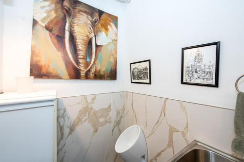 a bathroom with a white toilet and paintings on the wall at 3BR Charlotte Escape Pool Hot Tub Theater in Charlotte