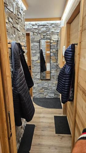 Cette chambre est dotée d'un mur en pierre et d'un couloir avec des vêtements. dans l'établissement Val Thorens, plein Centre, 8 pers, 3 chb, vue ouf!, à Val Thorens