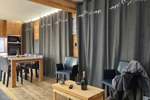 - une salle à manger avec une table, des chaises et des rideaux dans l'établissement Val Thorens, plein Centre, 8 pers, 3 chb, vue ouf!, à Val Thorens