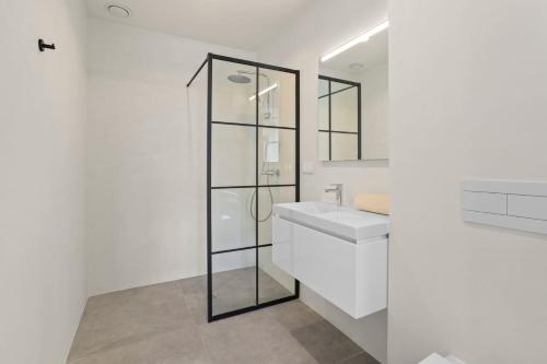 a white bathroom with a sink and a mirror at Bonaire Beach Apartment 5 with shared pool and diving facilities in Kralendijk