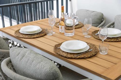 a wooden table with plates and wine glasses on it at Bonaire Beach Apartment 5 with shared pool and diving facilities in Kralendijk