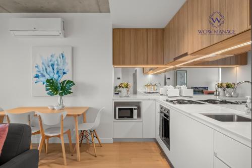 a kitchen with white cabinets and a table and a dining room at WOW Apartment on Hancock Southbank in Melbourne