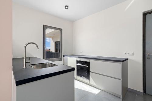 a white kitchen with a sink and a mirror at Bonaire Beach Apartment 12 with communal pool and diving facilities in Kralendijk