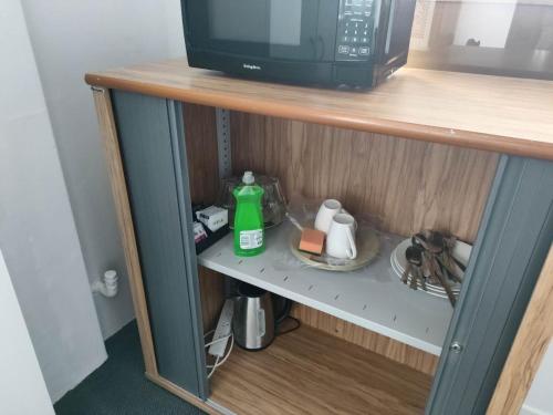 un microondas en la parte superior de un estante en 4 Beds including 1 Double Bed, 1 Single Beds, 2 Double Sofa Beds, Suite 2, 37 Totara Avenue, New Lynn, en Auckland