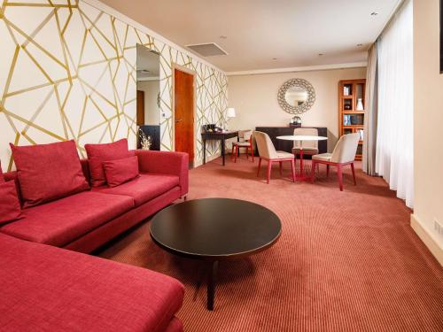 a living room with a red couch and a table at Holland House Hotel Cardiff By Sunday in Cardiff
