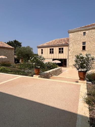 un bâtiment en briques avec deux plantes en pot dans une cour dans l'établissement Manoir - Domaine Lassalle Saint-créac, à Saint-Créac