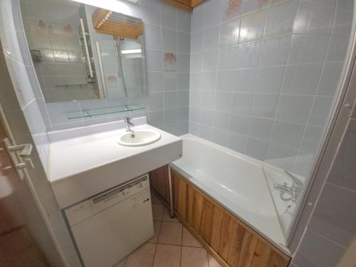 une salle de bain avec un lavabo, une baignoire et un miroir dans l'établissement Studio confort 3 pers, proche pistes, balcon sud-ouest - FR-1-452-26, aux Menuires