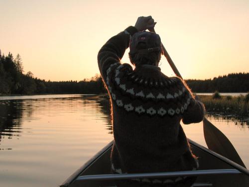 a man is paddling a canoe on a lake at Kustleden Vandrarhem in Strömsbruk
