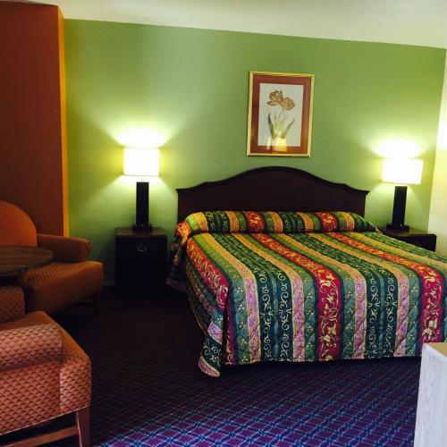 a bedroom with a bed with a colorful bedspread and two lamps at Hacienda Motel in Yuma