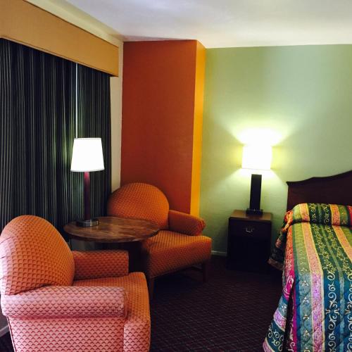 a hotel room with a bed and a chair and a table at Hacienda Motel in Yuma