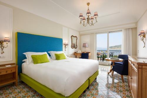 a bedroom with a large bed with a blue headboard at Grand Hotel Capodimonte in Sorrento