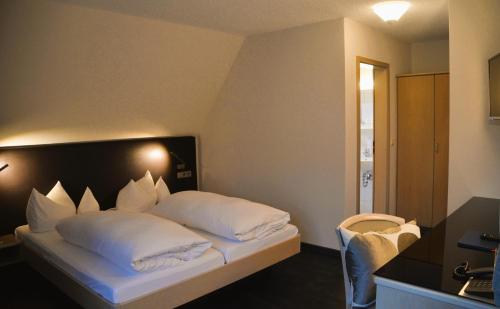 a hotel room with a bed with white pillows at Castell Hotel & Restaurant in Leinsweiler