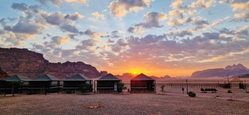 a sunset over a group of tents in the desert at Shakria Bedouin Life Camp in Wadi Rum