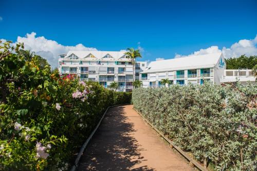 a path through a garden with buildings in the background at Studio à la plage in Le Gosier