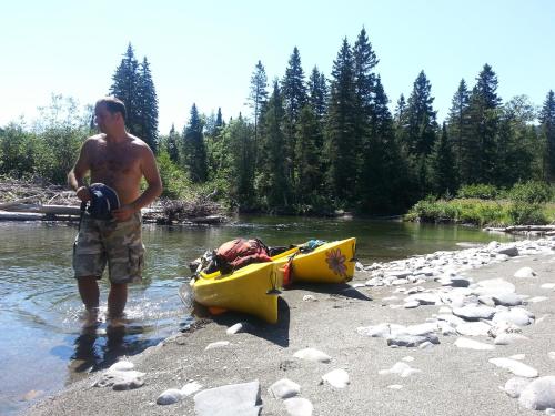 a man standing in the water next to a kayak at Bed and Breakfast Du Repos in Saint Quentin