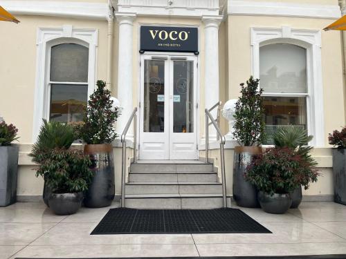 a door to a store with potted plants in front of it at voco The Clifton Folkestone by IHG in Folkestone