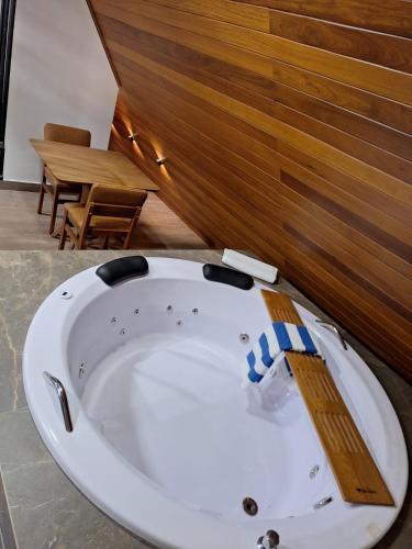 a white bath tub in a room with a wooden wall at Eros lodge in Jaboticatubas