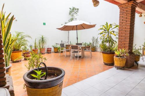 a patio with a table and an umbrella and potted plants at Hotel Magda in Oaxaca City