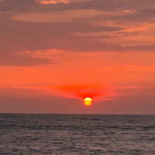 a sunset over the ocean with the sun in the sky at Marari Helen Villa in Mararikulam