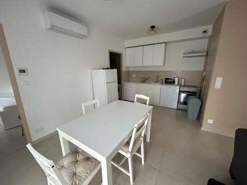 une cuisine blanche avec une table et des chaises blanches dans l'établissement Appartement avec jardin, à Châteauneuf-de-Galaure