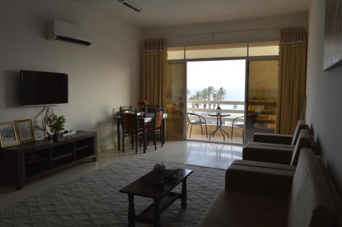 a living room with a couch and a tv and a table at Beautiful Salalah Beach Apartments - 1 by Beautiful Salalah Tours in Salalah