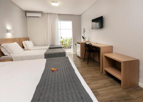 ein Hotelzimmer mit zwei Betten und einem Fernseher in der Unterkunft Tropikalya Gold Hotel in Balneário Camboriú