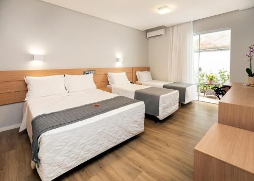 Una habitación de hotel con dos camas y una ventana. en Tropikalya Gold Hotel, en Balneário Camboriú