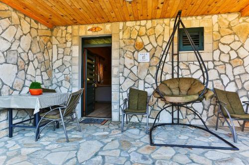 a patio with chairs and a table and a stone wall at Elite Apartments in Kolašin