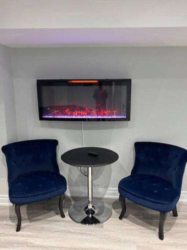 two chairs and a table in a room with a fireplace at Ravine Retreat - 3RM Suite, 2BD, 1 WR, Pool, Sauna in Whitby