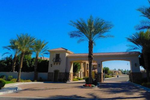 a palm tree in front of a building with an arch at Gated townhouse with heated pool, hot tub, near US60 in Mesa
