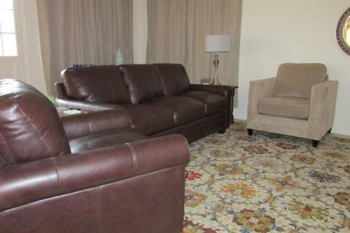 a living room with a leather couch and a chair at Cozy house near I-10 with pool heater, hot tub, BBQ in Goodyear