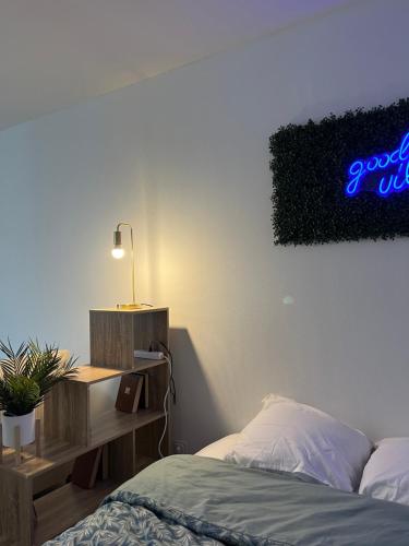 - une chambre avec un lit et un bureau avec un panneau de néon dans l'établissement Appartement Chill & confort, à Saint-Dizier