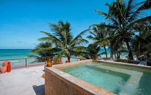 a swimming pool on the beach with palm trees and the ocean at La Zebra Tulum, a Small Luxury Hotel in Tulum
