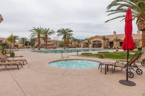 a resort pool with chairs and a red umbrella at Gated townhouse with 2 suites, heated pool, hot tub in Mesa