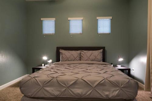 a bedroom with a large bed with three windows at Gated townhouse with 2 suites, heated pool, hot tub in Mesa