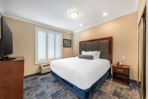 a bedroom with a large bed and a flat screen tv at Best Western PLUS Avita Suites in Torrance