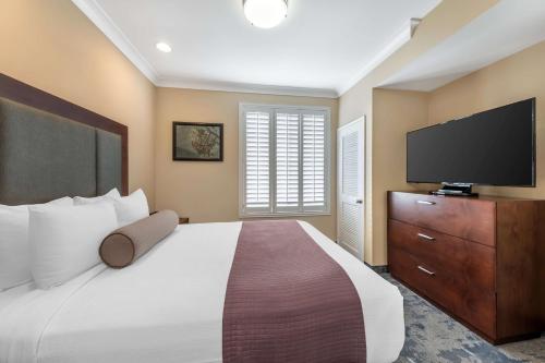 a bedroom with a large bed and a flat screen tv at Best Western PLUS Avita Suites in Torrance