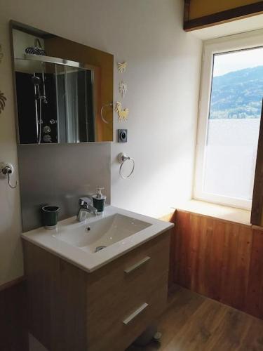 une salle de bain avec un lavabo et une fenêtre dans l'établissement Appartement cosy en duplex, à Taninges