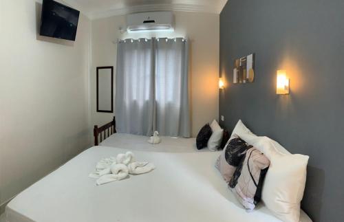 a bedroom with a white bed with two towels on it at Pousada Recanto Som do Mar in Caraguatatuba