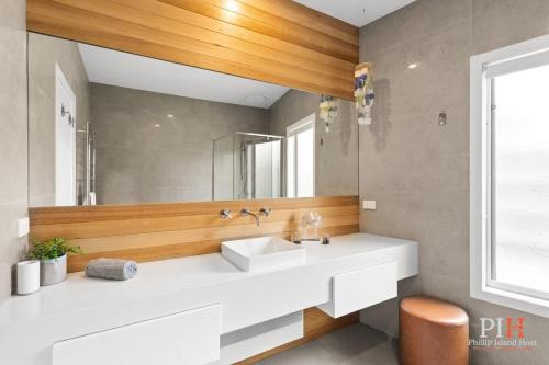 a bathroom with a white sink and a mirror at Coastal Family Retreat in CW in Cape Woolamai