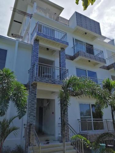 a tall white building with balconies and palm trees at Marlene's Hilltop Villa in Cebu City