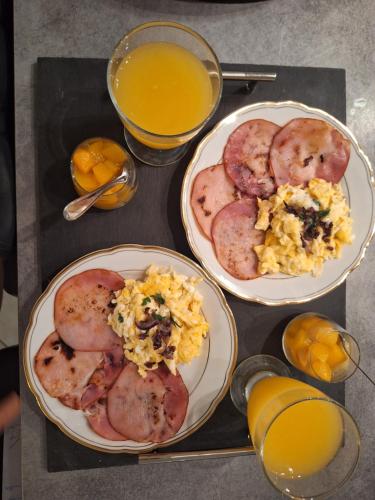 een tafel met 2 borden ontbijtproducten en jus d'orange bij Joli studio 25m2 avec cuisine in Chantemerle-sur-la-Soie
