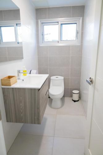 a bathroom with a toilet and a sink and a window at Ka' Romana Residences in El Soco