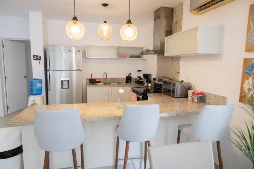 a kitchen with white chairs and a counter top at Ka' Romana Residences in El Soco