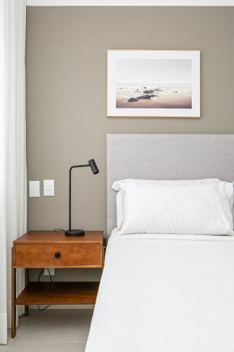 a bedroom with a bed and a table with a lamp at Cannes Club by Viva - Residencial a 200m da praia Ingleses do Rio Vermelho in Florianópolis