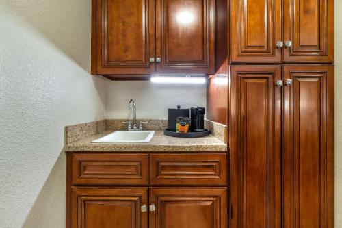 a kitchen with a sink and wooden cabinets at Best Western John Muir Inn in Martinez